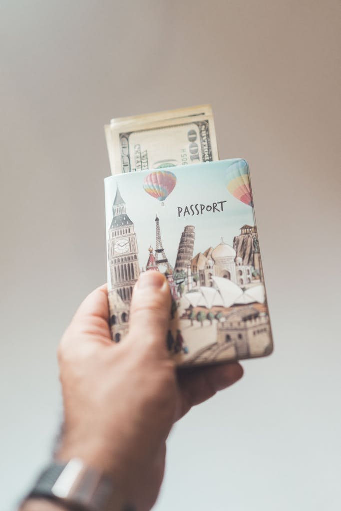 Crop anonymous person showing banknotes with creative passport in hand on beige background