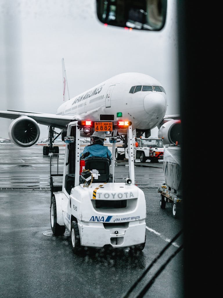 Airport Shuttle Tip? How Much To Tip Airport Shuttle 2 Airport ground crew operating a vehicle in front of a parked airliner on a rainy runway.